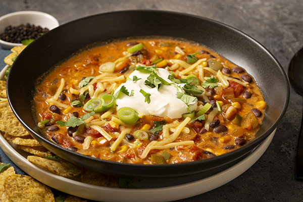 Taco Soup Topped with Melted Cheese, Sour Cream and Crunchy Corn Chips